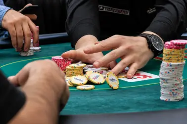 Poker players with stacks of chips at a poker table during a hand