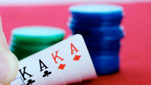 A player checking their cards on a red poker table, holding double-suited K♣, A♣, K♦, A♦, with green and blue chip stacks in the background, representing a perfect Omaha hi-lo situation