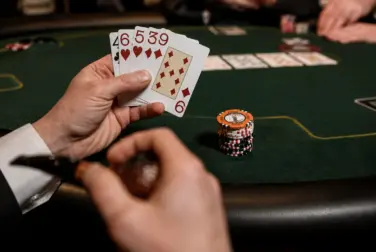 A poker player holding a five-card starting hand at a green casino table, illustrating 5 Card PLO poker