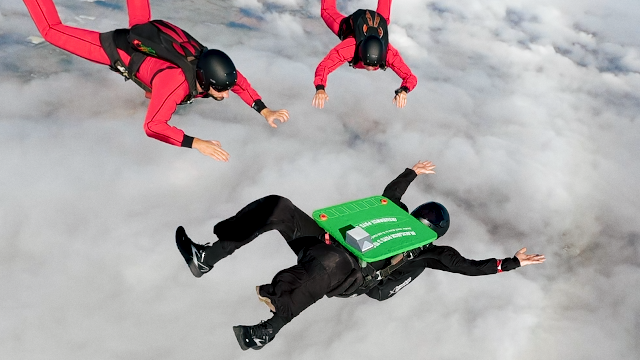 Four professional skydivers performing a mid-air blackjack stunt with a custom-built table above Northamptonshire